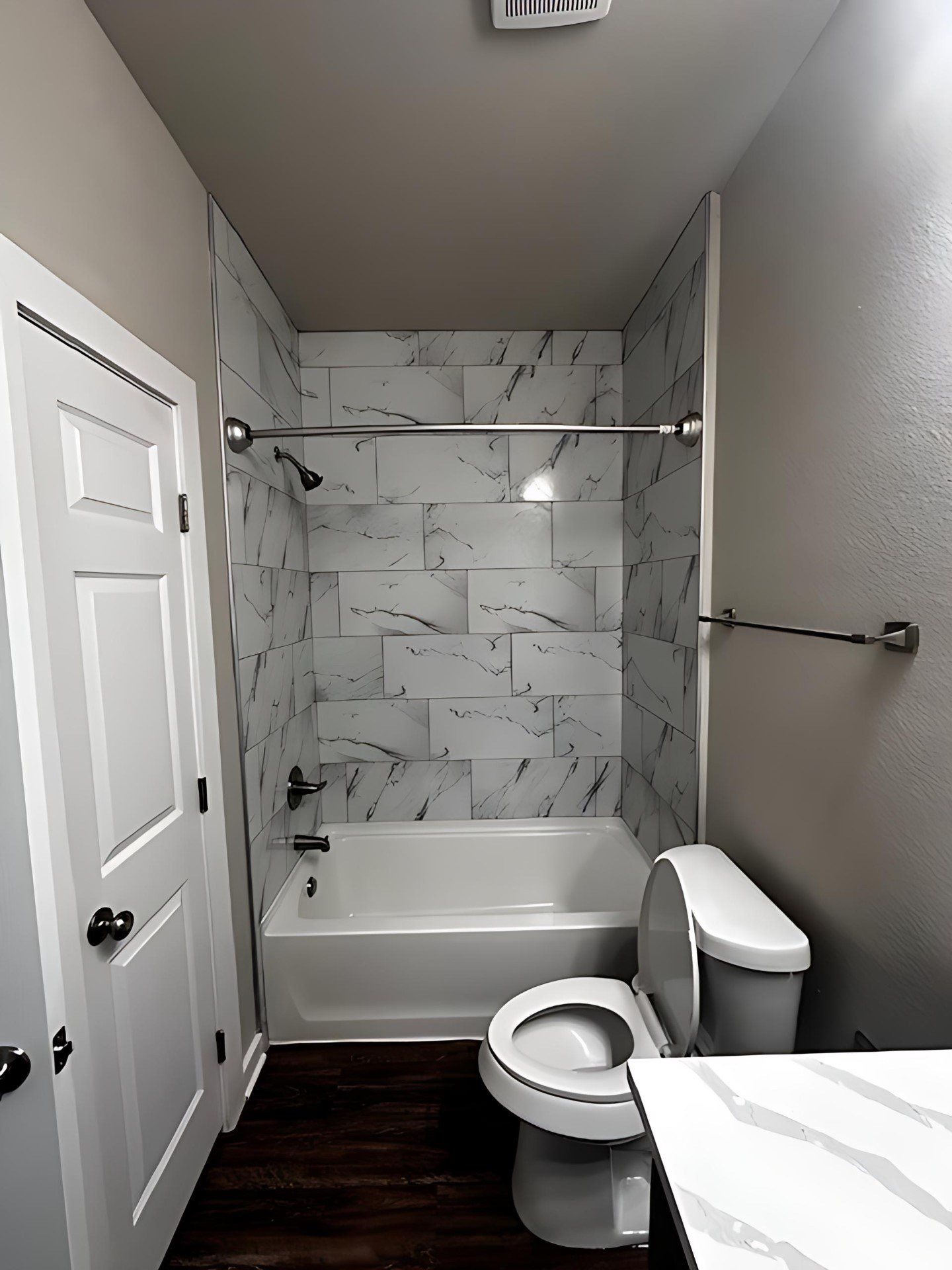 A white bathroom with a marble tile shower.